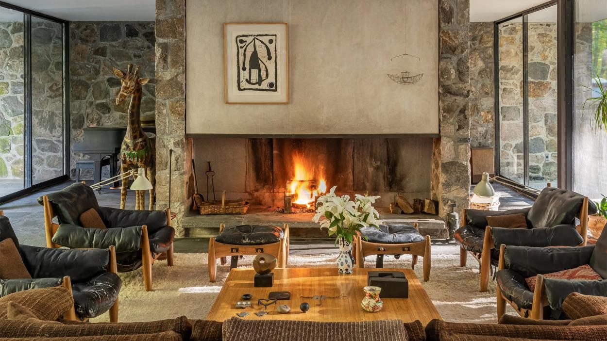 A modern glass-filled livingroom with a fireplace in New Canaan Connecticut, built by renown designer Eliot Noyes
