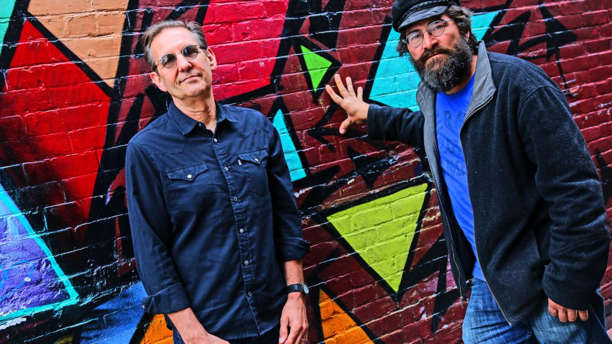 Both members of Soule Monde pose in front of an art mural